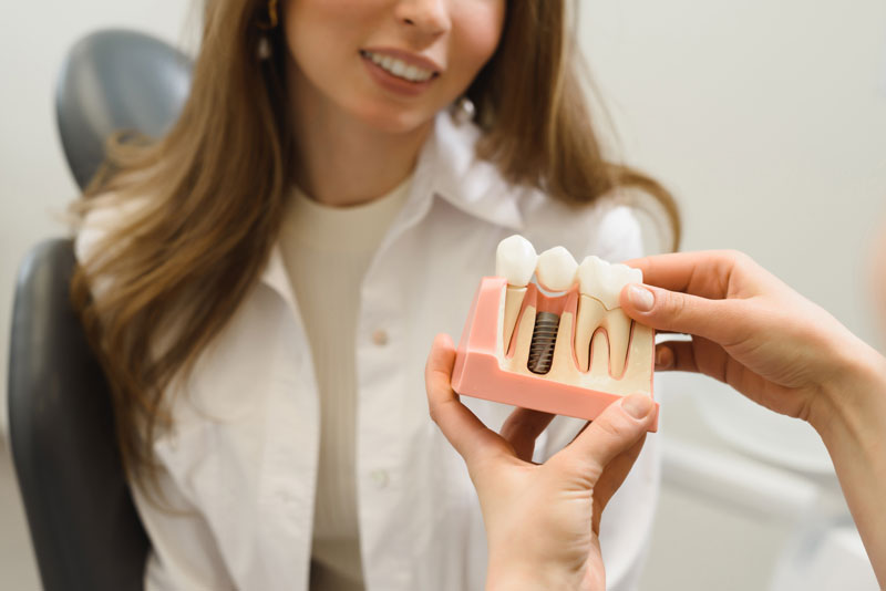 Dental Patient Getting Shown A Dental Implant Model During Her Consultation in Miami, FL